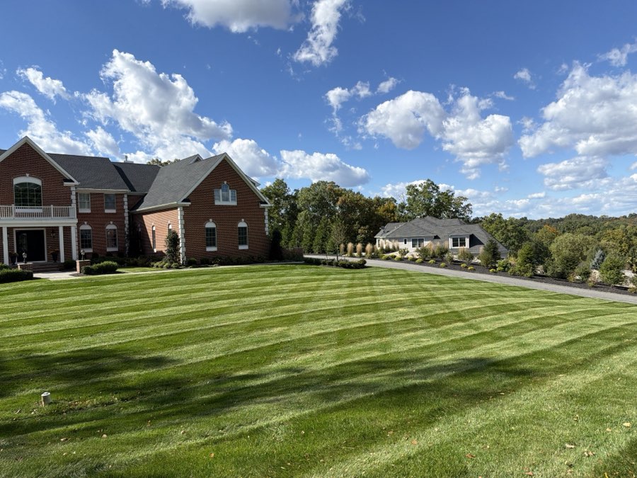 Wide striped lawn in front of a large brick home